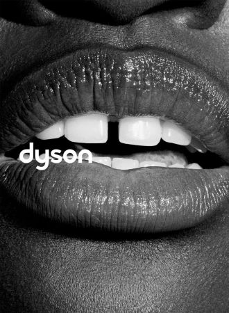 Extreme close-up monochrome photograph of lips and teeth with a tooth gap, featuring the Dyson logo.