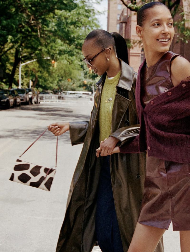 Two women walking down a city street, holding hands and carrying a patterned handbag, photographed by Daniel Arnold for Kate Spade FA26.