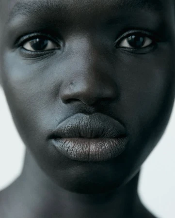 Close-up beauty portrait of a Black woman with natural skin and neutral lipstick for Chanel Beauty.