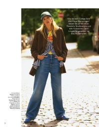 Model Kim Riekenberg wearing a brown blazer, striped shirt, wide leg jeans and baseball cap outdoors on a sunny street