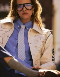Model wearing oversized sunglasses, blue shirt, striped tie, and star-studded cream jacket for Grazia Germany.