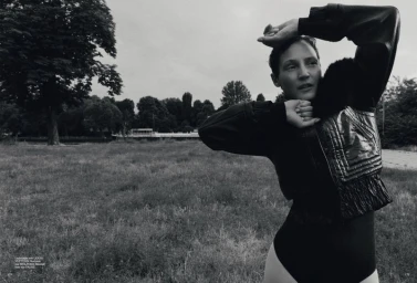Vicky Krieps posing in a black leather jacket in an open grassy park for Vogue Germany ALLES ANDERS editorial.