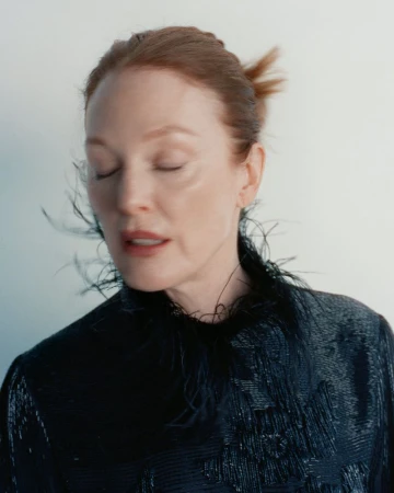 Julianne Moore wearing a dark feather-trimmed top against a white wall for Harper's Bazaar U.S.