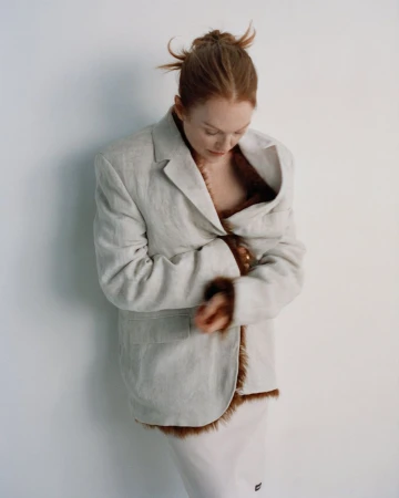 Julianne Moore wearing an oversized cream blazer with brown fur trim against a plain white wall