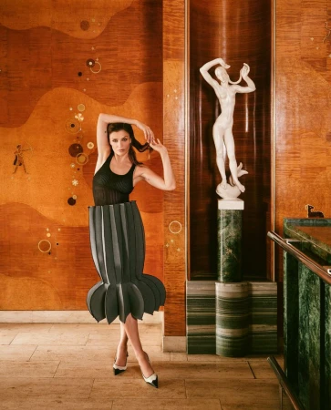 Helena Christensen posing in an architectural interior with wooden paneling and a white statue for Vogue Czechoslovakia