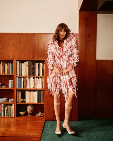 Model Helena Christensen in a red and white fringed tweed coat standing in a wood-paneled library for Vogue Czechoslovakia.