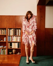 Model Helena Christensen in a red and white fringed tweed coat standing in a wood-paneled library for Vogue Czechoslovakia.