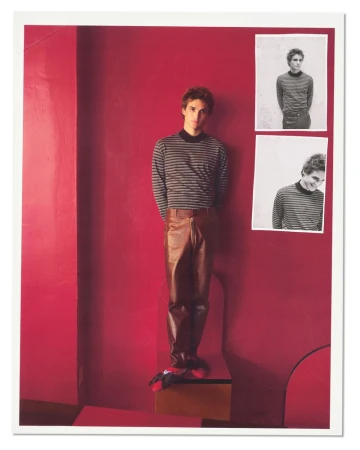 Man wearing a striped turtleneck and brown leather pants standing against a bold red wall with photo inserts