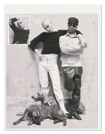 Black and white editorial photograph of two men posing with two dogs against a textured wall with an inset image
