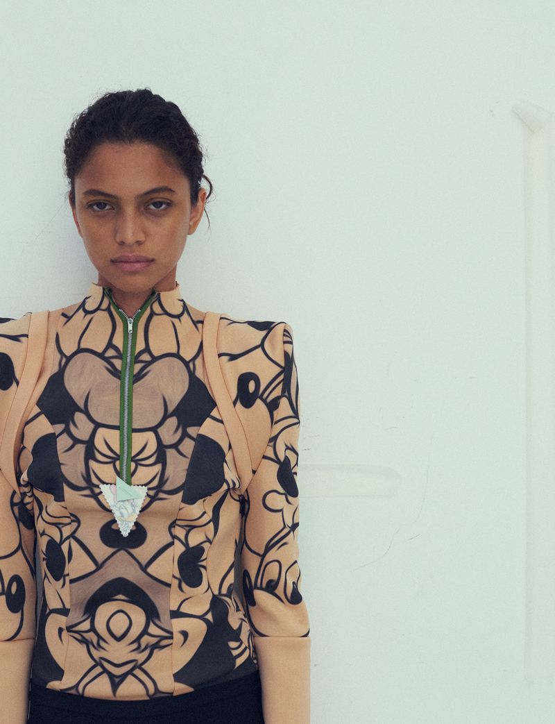 Portrait of a model wearing a patterned top with structured shoulders against a plain white background for Dazed Magazine.