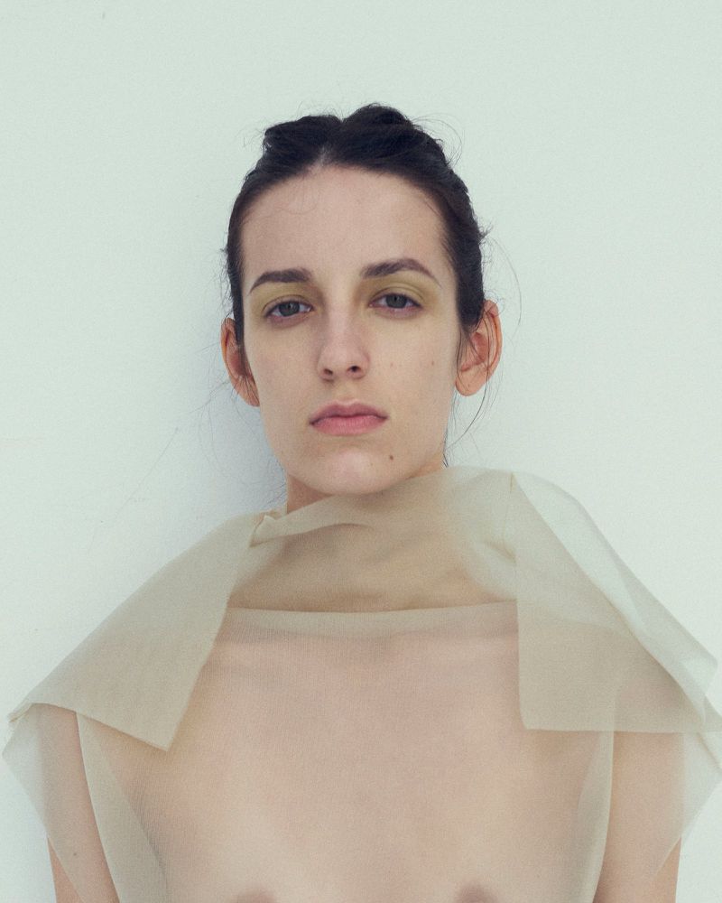 Portrait of a woman wearing sheer fabric against a plain white studio background for Dazed Magazine