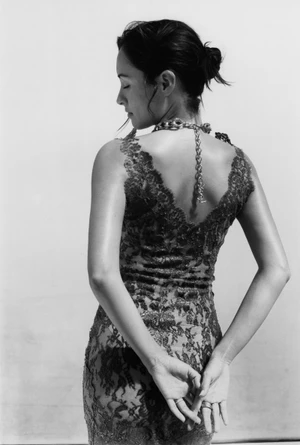 Model in lace dress with chain necklace posing against a light background for Pop Magazine