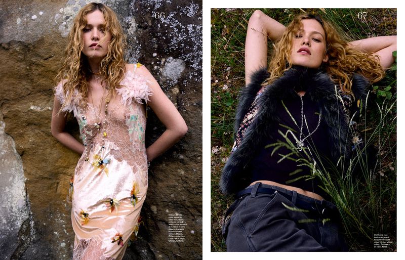 Model Liv Walters with curly blonde hair posing outdoors against a rocky stone wall and grassy terrain for Les Echos