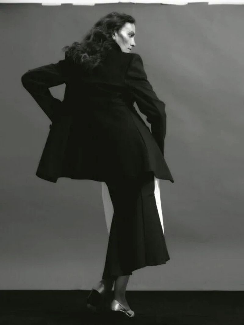 Model Laura Ponte wearing a black jacket and matching skirt against a grey seamless studio background for Forbes Spain.