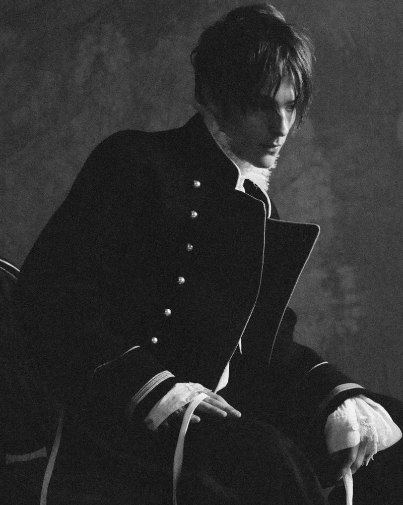 Corey Fogelmanis wearing a dark military-style jacket with white buttons for HERO Magazine editorial portrait
