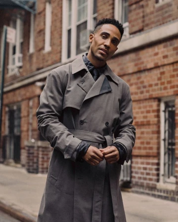 Man in a grey belted trench coat standing on a brick street for V Man fashion editorial