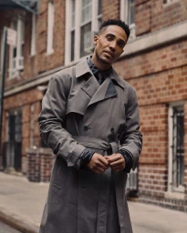 Man in a grey belted trench coat standing on a brick street for V Man fashion editorial