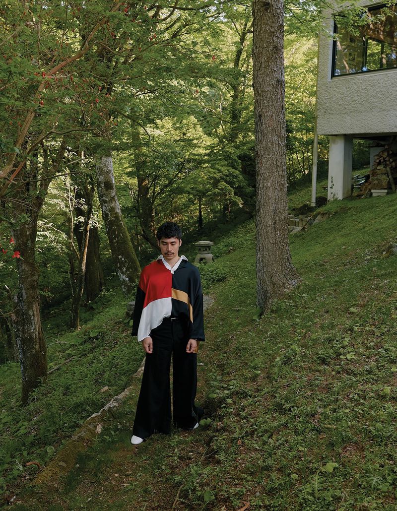 Man wearing a colour blocked top standing on a grassy path in a forest by Ivana Micic for CRUSHfanzine