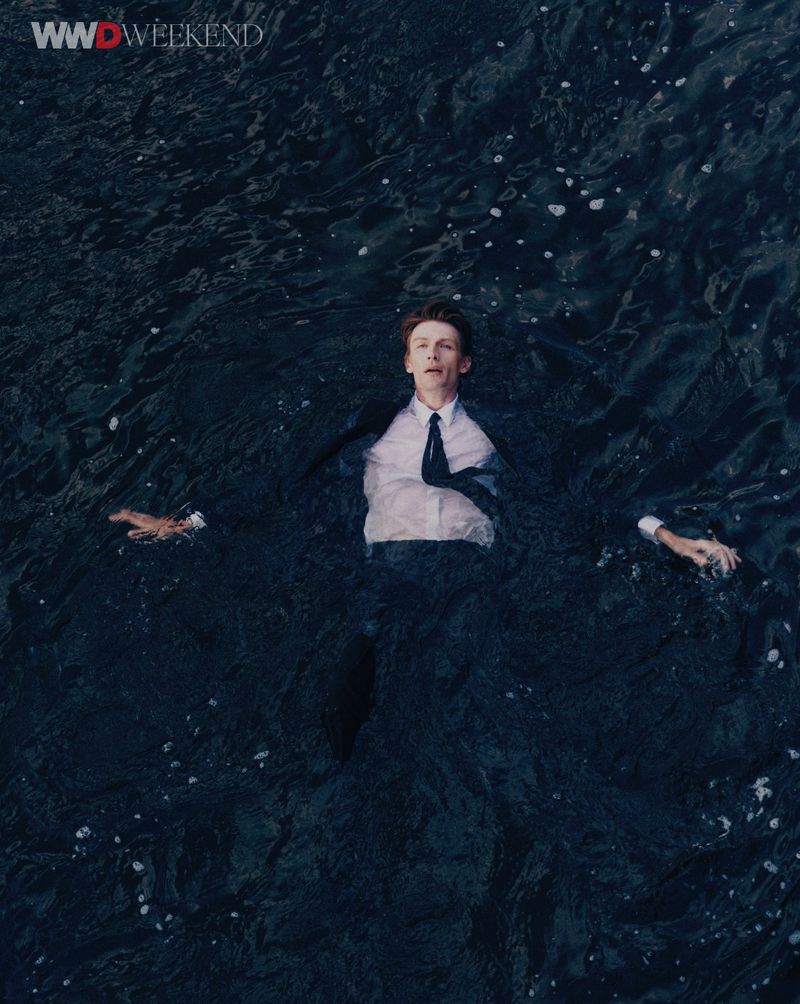 Man wearing a dark suit and white shirt floating in dark water for WWD Neo Noir editorial