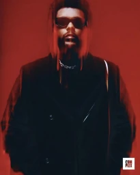 The Weeknd wearing dark sunglasses and a black coat against a vibrant red background in a portrait for Complex.