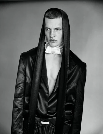 Monochrome portrait of male model Ivo Pelleboer wearing a hooded satin jacket and white bowtie for Esquire Portugal.