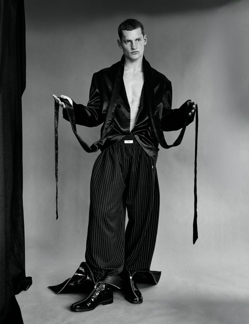 Monochrome fashion portrait of male model Ivo Pelleboer holding black satin jacket ties for Esquire Portugal.