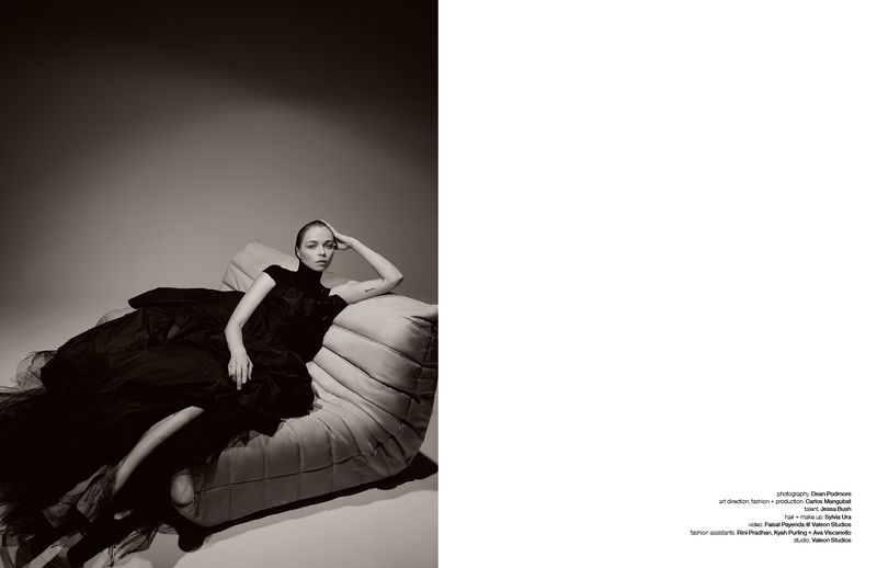 Woman in a black dress reclining on a quilted designer sofa against a neutral studio backdrop for Schon Magazine interview