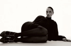 Model Jess Bush lying down in a dark dress and heeled shoes against a bright white background for Schön Magazine interview feature.