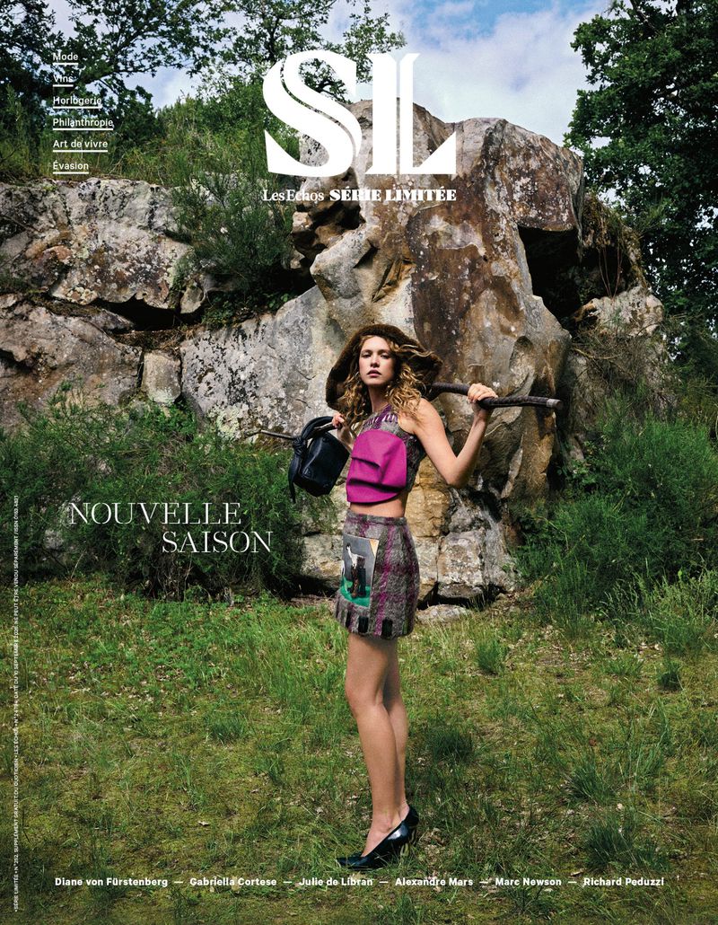 Model Liv Walters standing outdoors against a rocky cliff holding a dark handbag for a Les Echos editorial magazine cover.