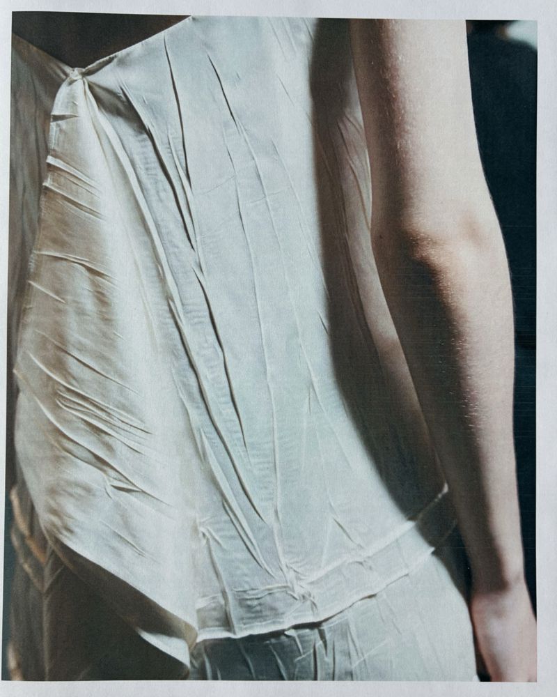 Close-up of a model wearing a textured white sleeveless top with draped fabric folds for Jil Sander Spring Summer 2027.