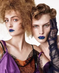 Two fashion models with voluminous hair and metallic blue lips posing together against a plain white background for Zara.