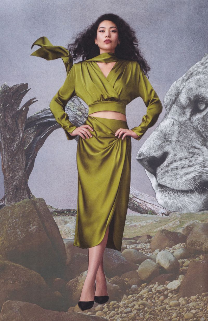 Model in olive green silk crop top and matching midi skirt standing against a collage backdrop featuring rocks and a lion head