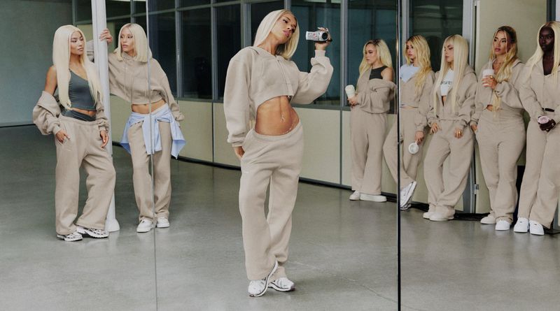 Group of women in beige fleece hoodies and sweatpants posing in front of a mirrored studio wall for Nike