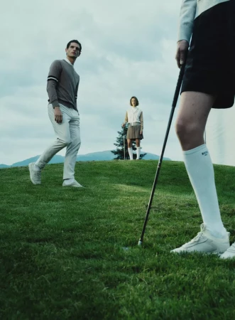 Three models on a grassy hill with golf attire under an overcast sky for HUGO GOLF, photographed by Gus&Lo.