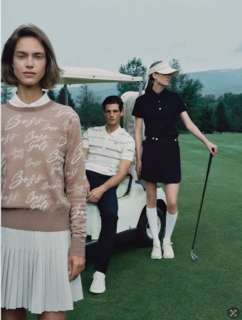 Three models wearing golf apparel posed on a golf course near a golf cart under an overcast sky.