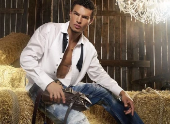 Model Noah Luis Brown posing in a rustic wooden barn with hay bales for the Dsquared2 Roxy Bag 2026 campaign.