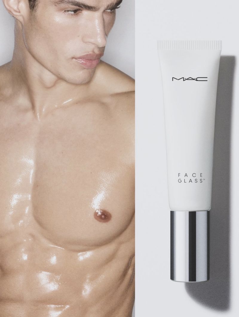 Close-up portrait of a man with glossy skin next to a MAC Face Glass cosmetic tube on a white background