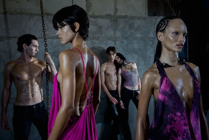 Group of models posing in industrial interior wearing magenta tops and dark trousers for Jaded London AW 26 campaign.