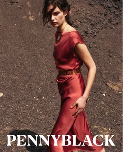 Model in a red silk dress walking on volcanic dark terrain for Pennyblack AI26 campaign
