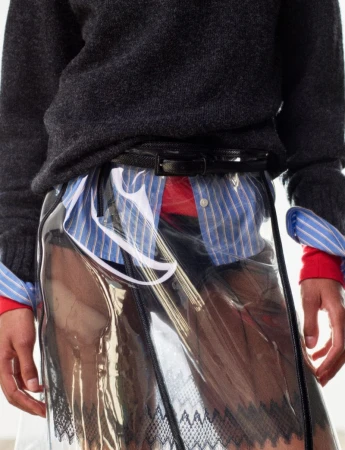 Model wearing a dark wool sweater, layered striped shirt, and clear vinyl skirt for Harper's Bazaar France editorial.