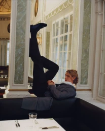 Actor George Mackay reclining with legs up on a banquette in an ornate interior for a GQ Magazine U.S. editorial by Joyce NG