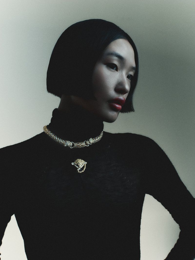 Model wearing a black turtleneck and gold necklace against a neutral background for Seduction Magazine editorial.