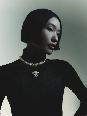 Model wearing a black turtleneck and gold necklace against a neutral background for Seduction Magazine editorial.