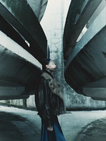 Model Daga Ziober wearing a dark jacket standing between massive concrete brutalist structures for Seduction Magazine