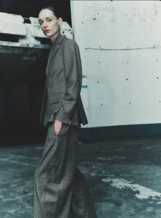 Model wearing a grey trouser suit standing against an industrial concrete wall in a fashion cover editorial by Gus&Lo for Sèduction Magazine
