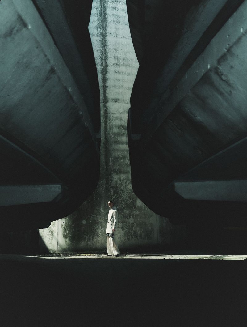 Model standing beneath massive curved concrete bridge structures in Seduction Magazine editorial cover