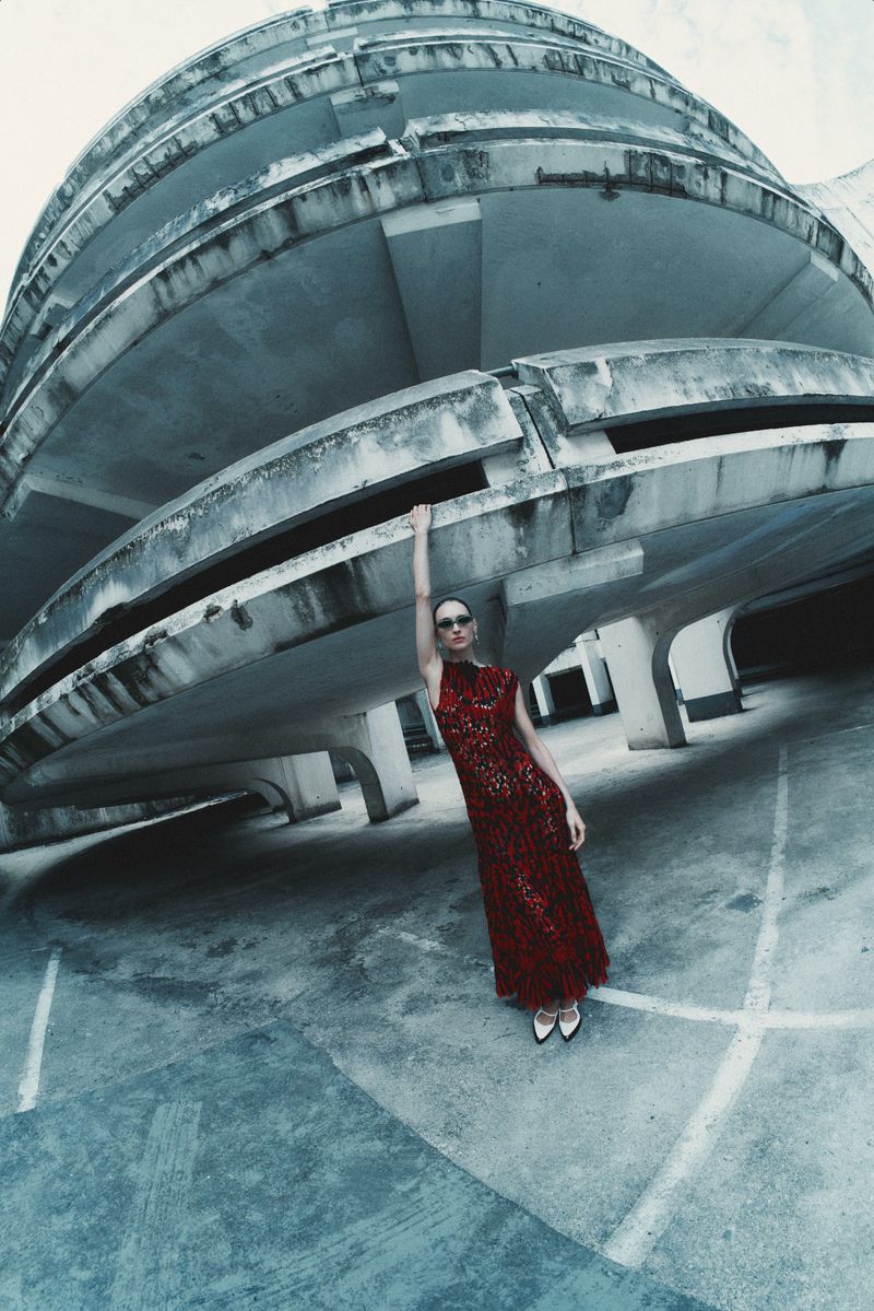 Model Daga Ziober wearing a red patterned dress in a concrete car park shot with a wide fisheye lens perspective