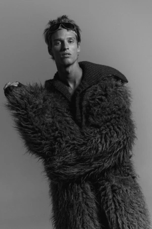 Model wearing a textured shaggy coat and dark sunglasses against a plain neutral background for Numero Netherlands.