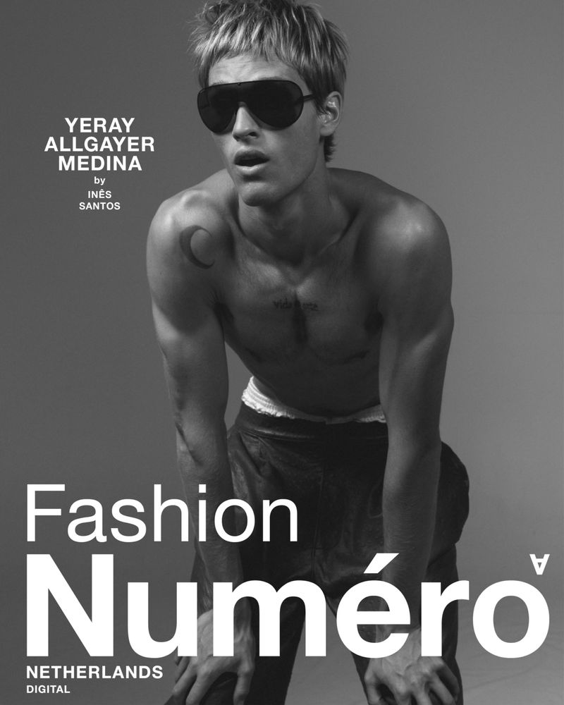 Monochrome portrait of shirtless male model wearing oversized black sunglasses against a solid grey background