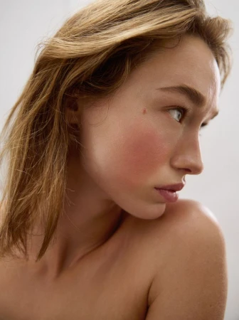Close-up portrait of a woman with blonde hair looking away against a neutral background
